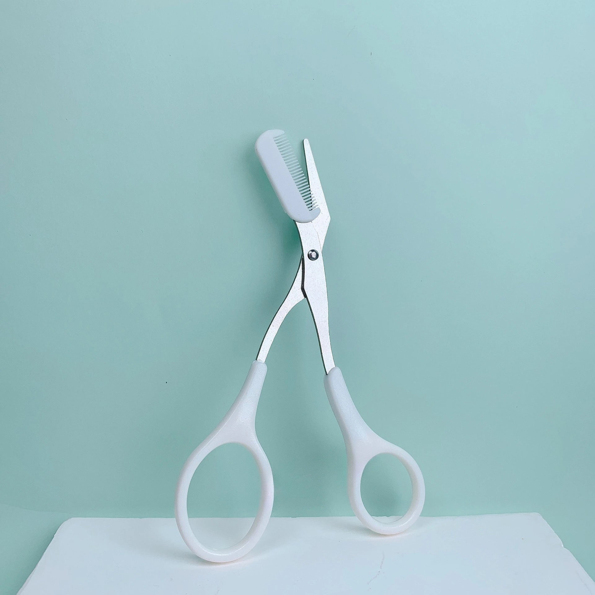 Eyebrow trimming scissors with built-in comb.