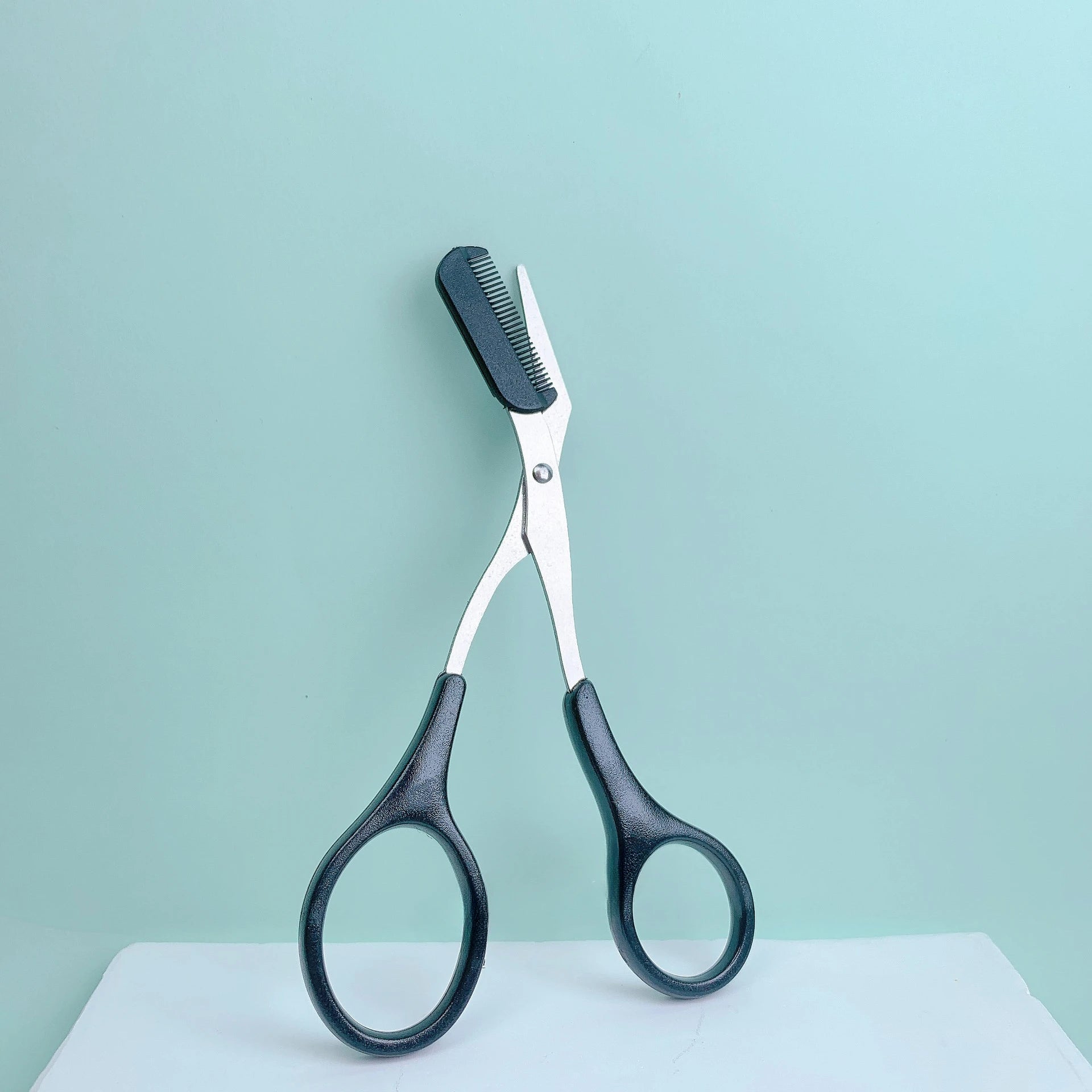 Eyebrow trimming scissors with built-in comb.